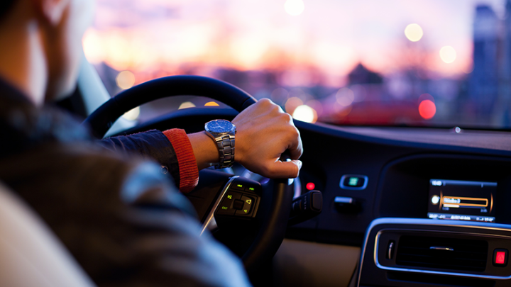 Over the shoulder view of a man driving his car at dusk. 