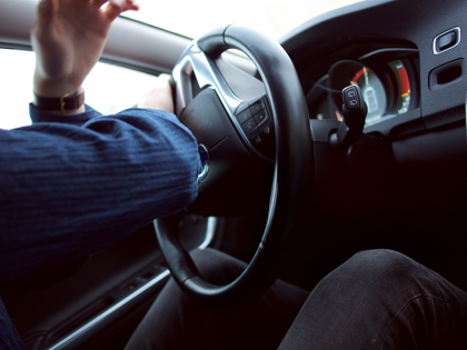 Closeup of a male hands at the stearing wheel of a car. His hands are in process of turning the wheel in a way that looks urgent.