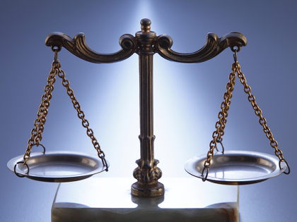 The scales of justice sitting on a blue background. 