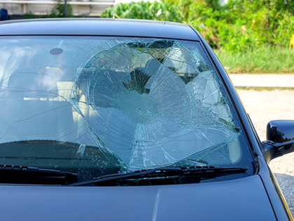 A black car with a windshield shattered and caved in.